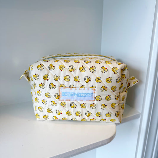 Cosmetic bag with duck pattern on a white shelf